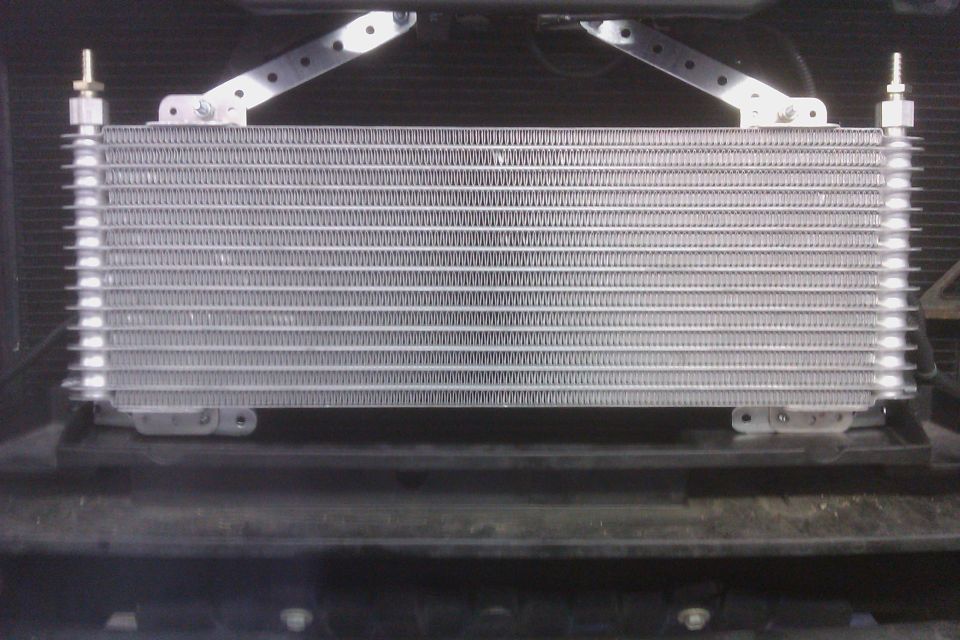 Transmission cooler mounted in front of radiator, with metal brackets holding it in place