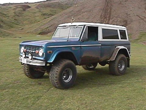 1974 Ford Bronco - This 1974 Ford Bronco is shown in a three-quarter front view, parked on a grassy area with a hill in the background.