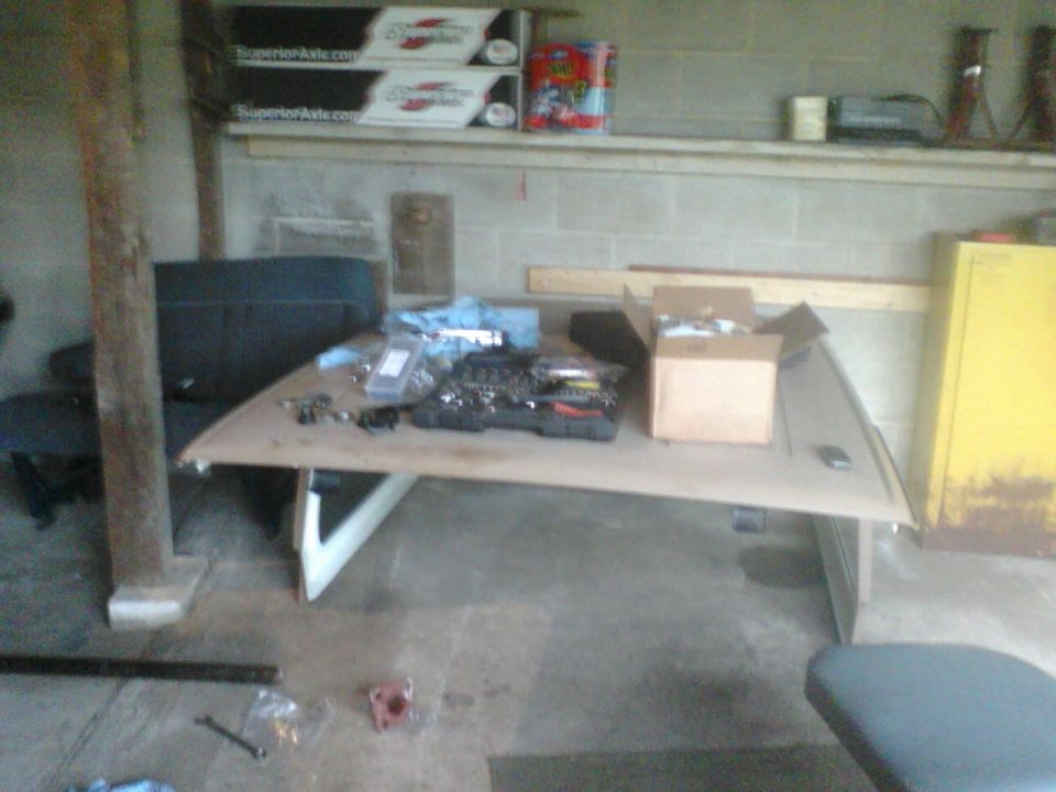 Workbench with assorted parts, tools, and boxes in a garage setting
