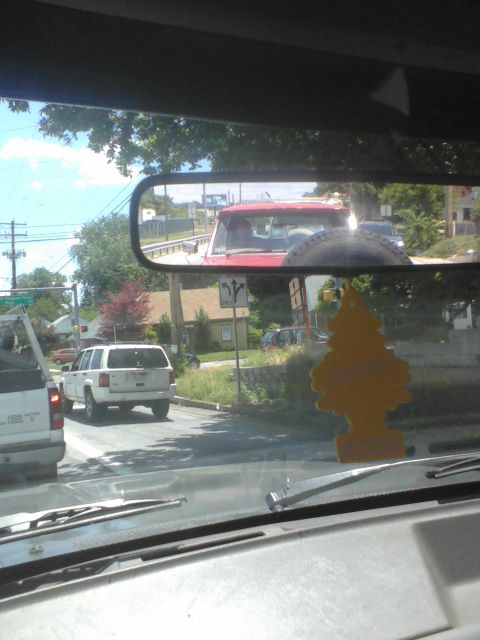 1988 Ford Bronco - A red SUV is seen from inside another vehicle, with a spare tire mounted on its rear.