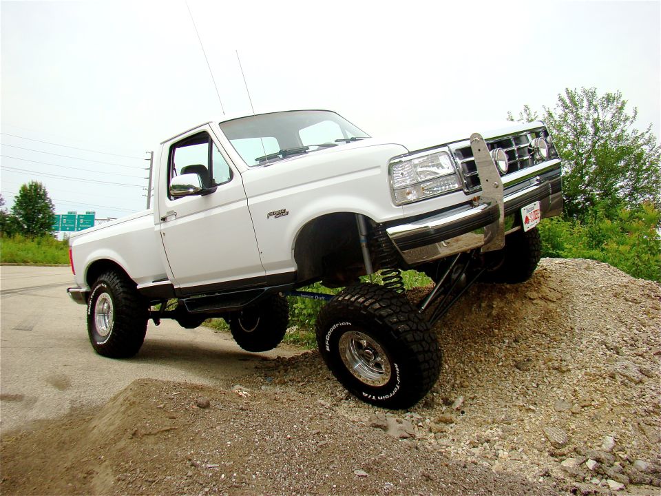 White lifted Ford F-150 with chrome brush guard posed on a dirt mound