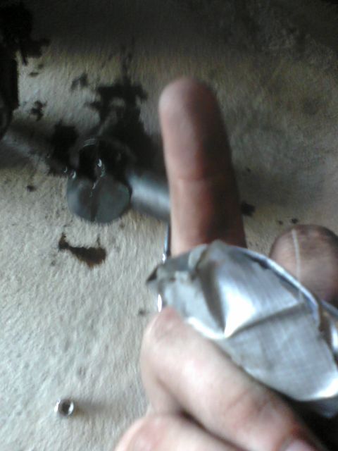 1988 Ford Bronco - Close-up of a mechanic's hand holding a rag near a bolt, with oil stains visible.