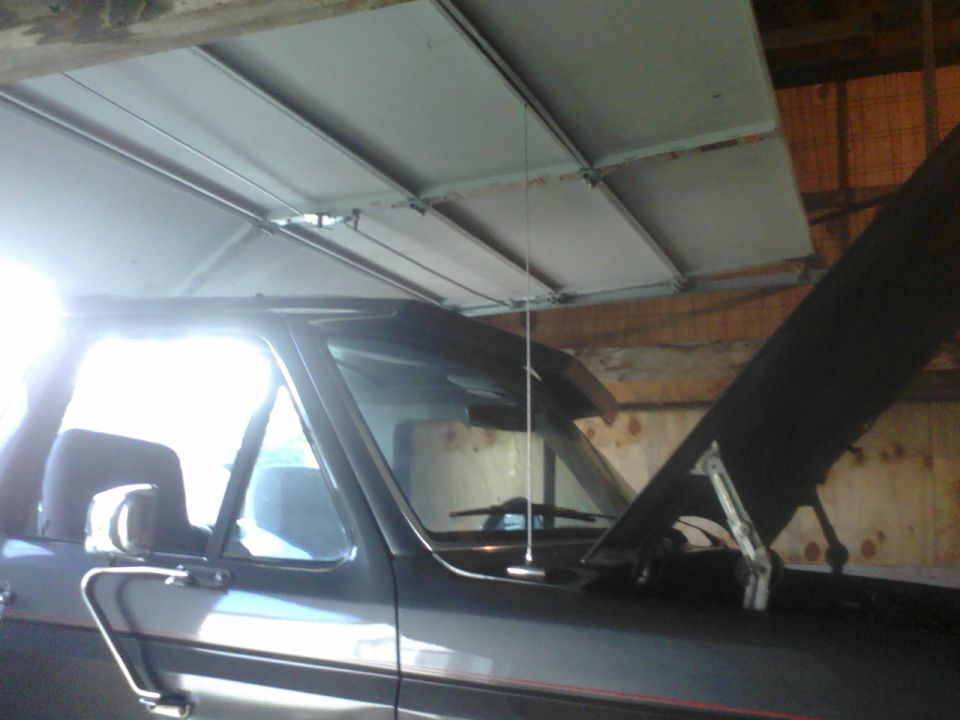 1988 Ford Bronco parked inside with hood open. Side view shows driver's door, mirror, and antenna
