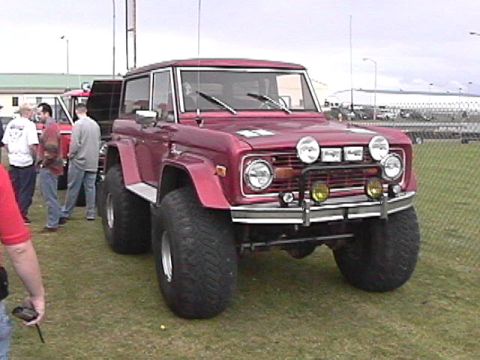 1974 Ford Bronco - A lifted Ford Bronco sits on a grassy field with other vehicles and people nearby.