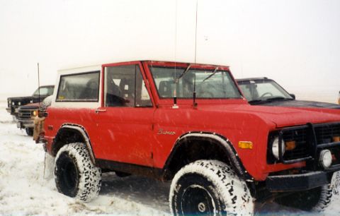1974 Ford Bronco - A red and white 1974 Ford Bronco is parked in the snow, with another vehicle visible behind it.