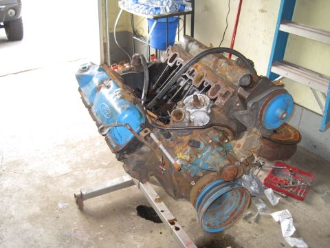 1979 Ford Bronco - A rusty Ford V8 engine sits on a stand, ready for work or parts.