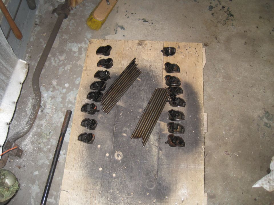 Engine rocker arms and pushrods laid out on a wooden board