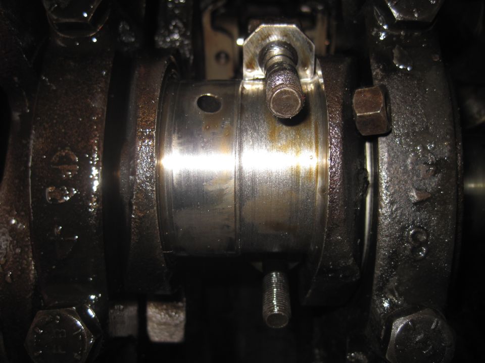 Engine crankshaft bearing with oil and bolts visible