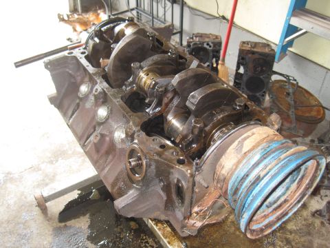 1979 Ford Bronco - Disassembled engine block and cylinder heads sit on a stand in a workshop.