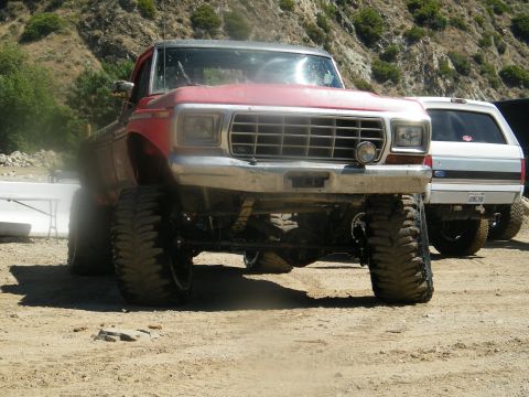 1982 Ford Bronco - A red lifted 1979 Ford F-150 truck is parked outdoors next to another vehicle.