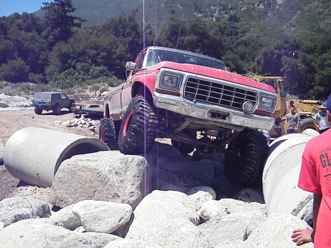 1982 Ford Bronco - Modified pickup truck attempting an obstacle course with other vehicles present.