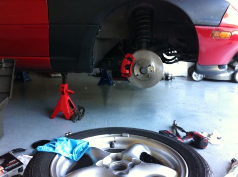 1990 Mazda Miata - The car is up on jack stands for brake maintenance, with tools and a tire nearby.
