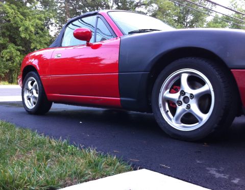 1990 Mazda Miata - This 1990 Mazda Miata features a red body with an unpainted black fender and a black soft top.