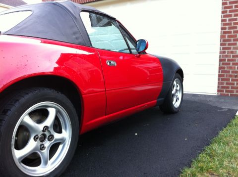 1990 Mazda Miata - Side view of a red 1990 Mazda Miata with contrasting black fender flares.