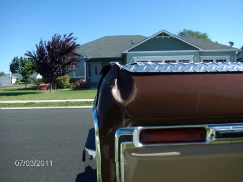 1979 Ford F-150 - The rear corner of a truck is visible, with a toolbox mounted on the bed rail. A house is in the background.