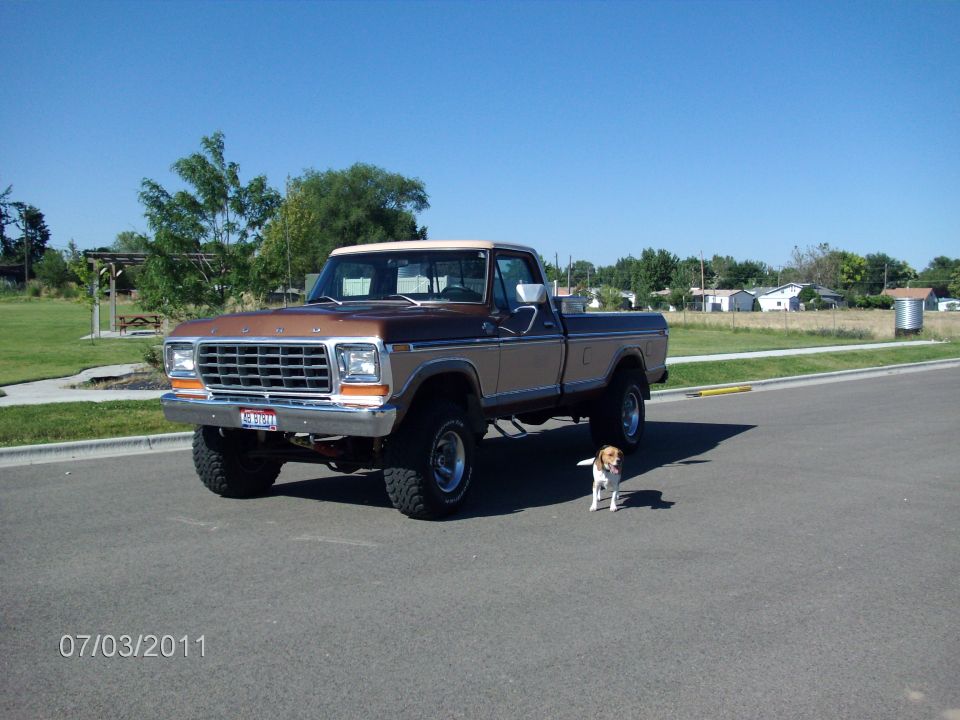 Brown and tan 1979 Ford F-150 pickup truck with a white roof, parked on asphalt with a beagle dog nearby