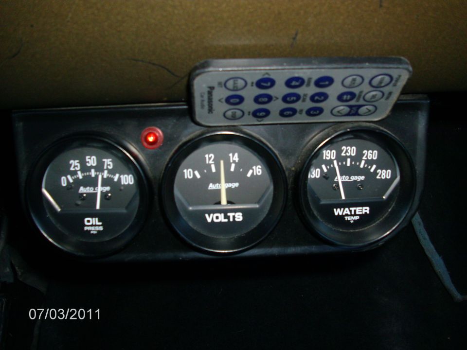 Dashboard gauges for oil pressure, volts, and water temp with a remote control on top