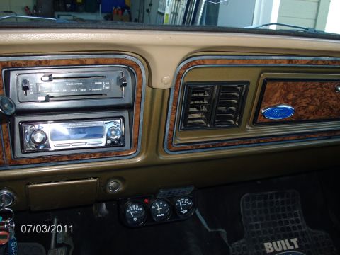 1979 Ford F-150 - Close-up of a vehicle's dashboard, showing the climate controls, an aftermarket stereo, and a Ford emblem.