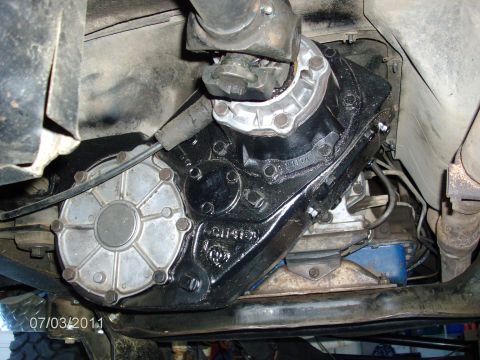 1979 Ford F-150 - Underside view of a vehicle's transfer case, showing its black housing and a silver circular cover.