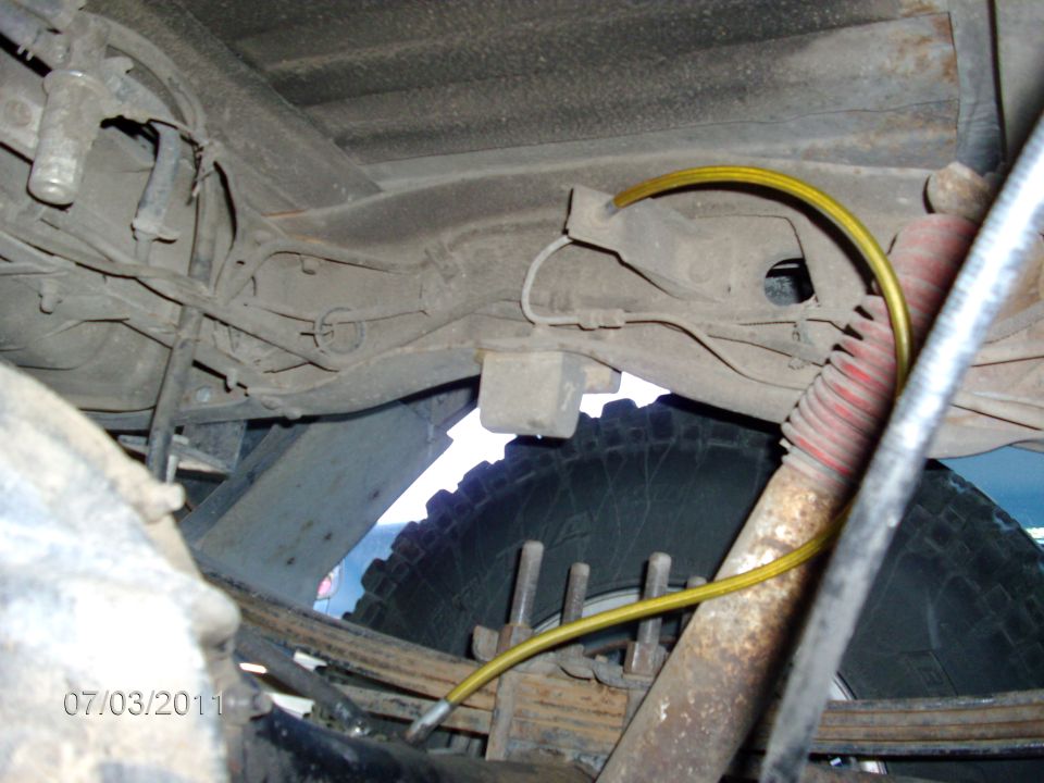 Undercarriage of a truck with leaf springs, shock absorber, and brake line. Date stamp 07/03/2011