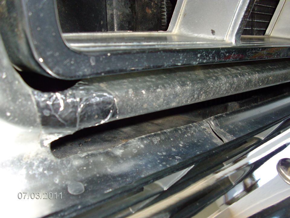 Close-up of a vehicle's chrome bumper and grille with visible damage