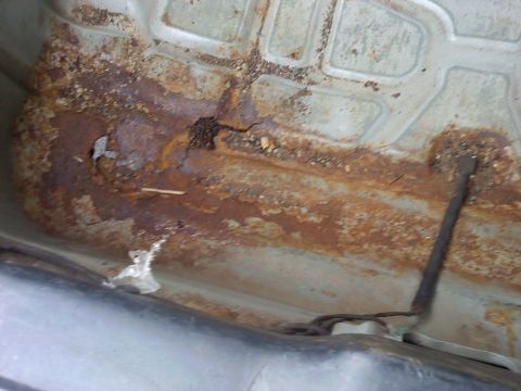 2000 Ford Crown Victoria - The undercarriage of a vehicle displays extensive rust damage and structural compromise.