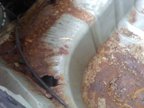 2000 Ford Crown Victoria - Significant rust and a hole are visible in the vehicle's frame, indicating it is a parts car.