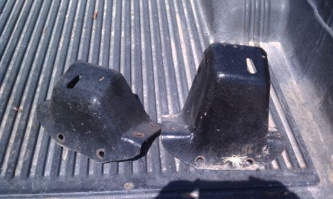 1979 Ford Bronco - Two black metal brackets are shown, likely for automotive use, against a ribbed background.