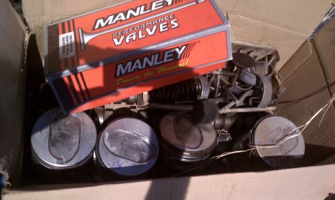 1979 Ford Bronco - Engine parts, including pistons and valves, are stored in a cardboard box.