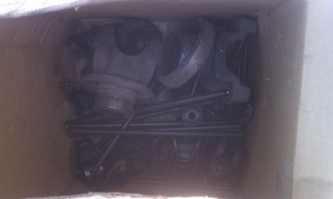 1979 Ford Bronco - A cardboard box filled with various metal automotive parts, including a brake drum and pushrods, is pictured.