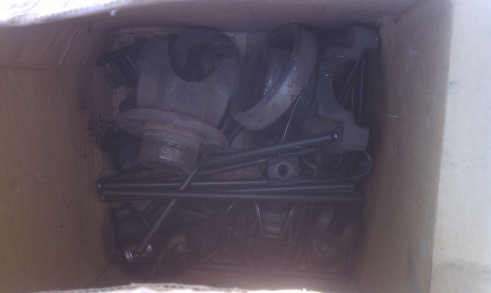 Box of assorted metal car parts, including what appears to be a brake drum and pushrods