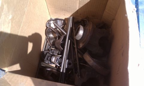 1979 Ford Bronco - A collection of engine components are piled inside a cardboard box, awaiting their next use.