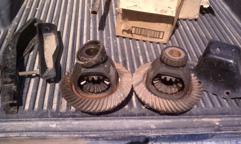 1979 Ford Bronco - Differential parts and brackets are laid out on a truck bed, with a cardboard box in the background.