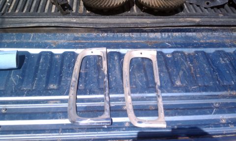 1979 Ford Bronco - Two tail light bezels are shown in the bed of a truck, with a Supermotors watermark at the bottom right.