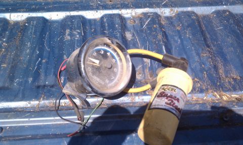 1979 Ford Bronco - ACCEL Super Coil and a tachometer are shown resting on a blue surface.