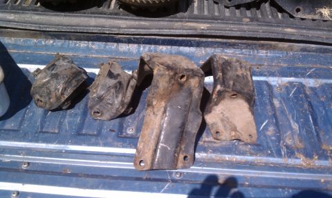 1979 Ford Bronco - Four engine mounts are displayed on a blue truck bed, likely for sale.