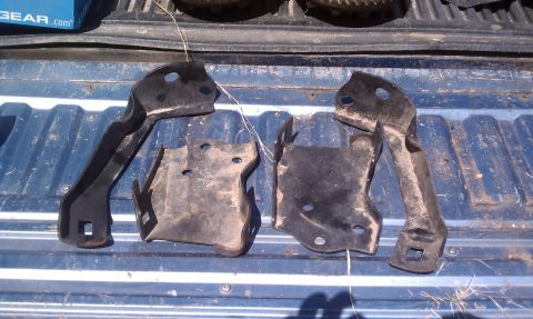 1979 Ford Bronco - Set of four metal brackets, likely for a vehicle, are shown on a truck bed.