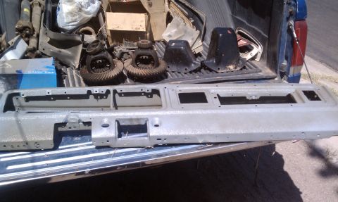 1979 Ford Bronco - Various automotive parts are organized in the bed of a pickup truck, ready for transport or sale.