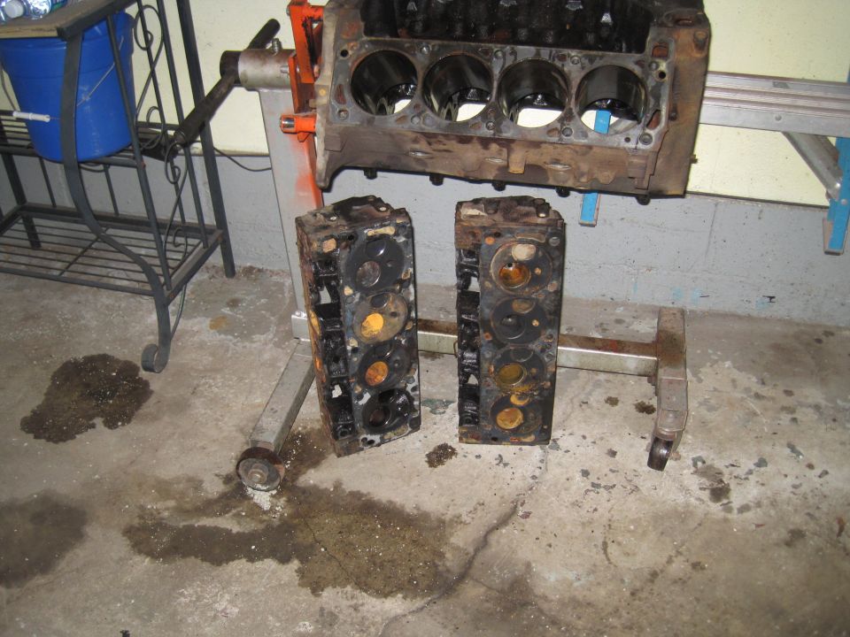 Engine block on stand with two cylinder heads beside it
