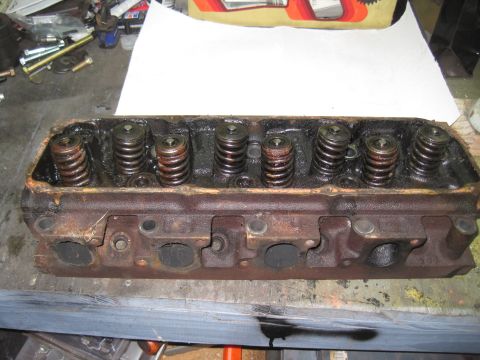 1979 Ford Bronco - A used engine cylinder head with visible valve springs sits on a workbench.