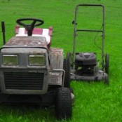 1989 Ford Bronco - Two lawn mowers, one a riding mower and the other a push mower, sit on a green, grassy field.