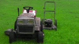 1989 Ford Bronco - Two mowers sit on a green lawn, one a riding mower and the other a push mower.