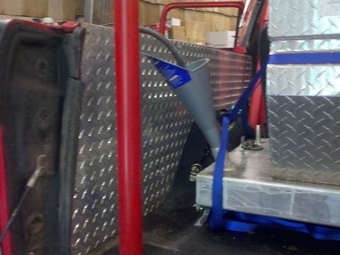 1979 Ford Bronco - A funnel is positioned to drain into a container inside a vehicle, with diamond plate and storage boxes visible.