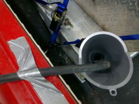 1979 Ford Bronco - A funnel and hose are strapped down in the cargo area of a vehicle.
