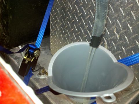 1979 Ford Bronco - A close-up view of liquid being poured through a funnel, held in place by straps.