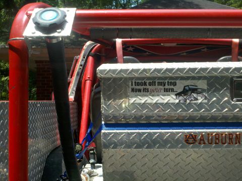 1979 Ford Bronco - A custom off-road vehicle is shown with a roll cage, a diamond plate toolbox, and a humorous sticker about removing the top.