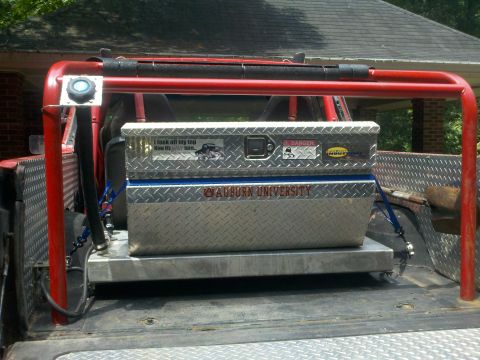 1979 Ford Bronco - Diamond plate toolbox secured with straps inside a truck bed with a red roll cage.