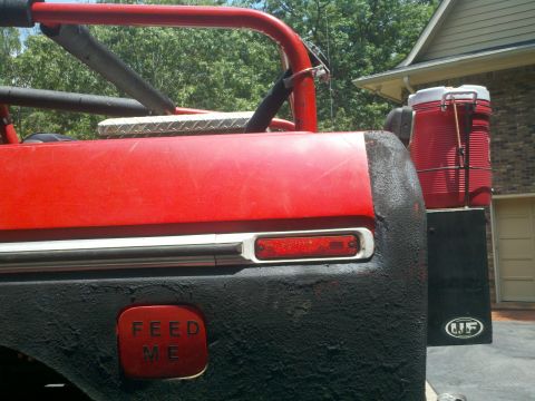 1979 Ford Bronco - The rear of a red Bronco shows a custom gas cap and a large cooler mounted on the tailgate.