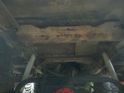 1979 Ford Bronco - The underside of a vehicle reveals its frame, suspension, and drivetrain components.