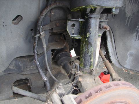 1992 Ford Taurus - Close-up view of the front suspension and brake assembly, including the strut, CV axle, and rotor. The SuperMotors.net logo is visible at t…